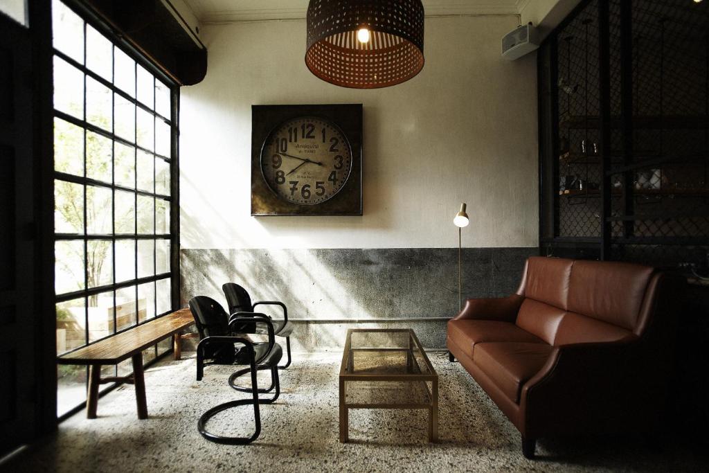 a living room with a couch and a clock on the wall at Your Fun Apartment in Tainan