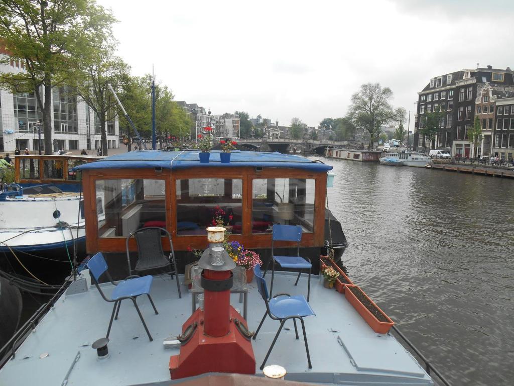 ein Boot auf einem Fluss mit Stühlen darauf in der Unterkunft Waterloo square river vieuw houseboat in Amsterdam