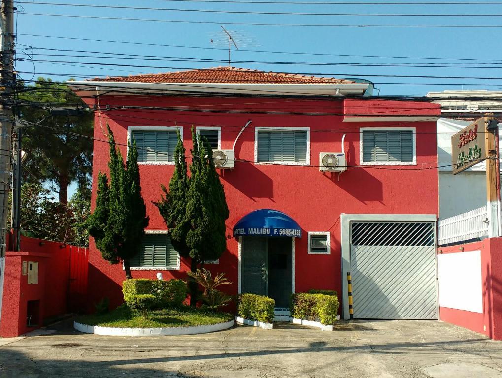 a red building with a door and trees in front at Hotel Malibu (ADULT ONLY) in Sao Paulo