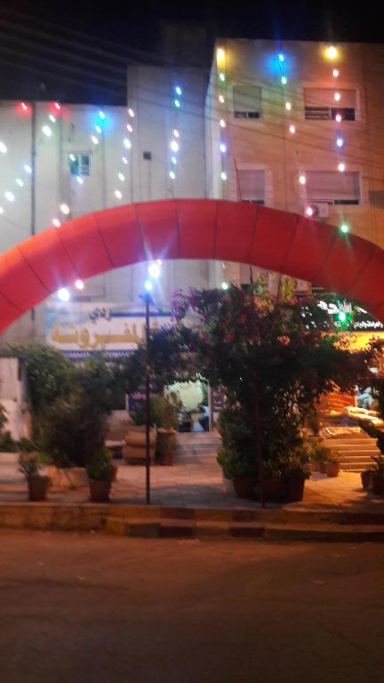 a red umbrella in front of a building at night at Al Seoudi Furnished Units in Az Zarqa