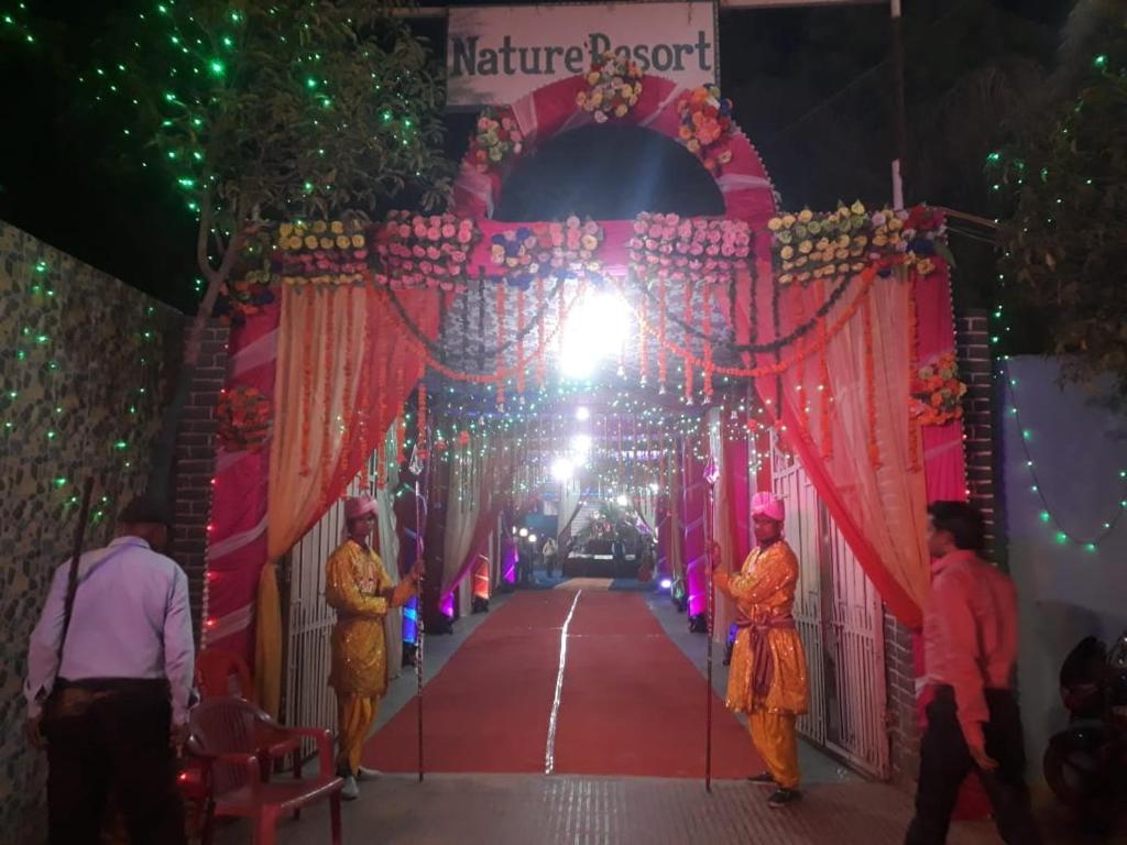 een tunnel versierd met lichten en mensen die op een rode loper lopen bij Nature Resort in Agra