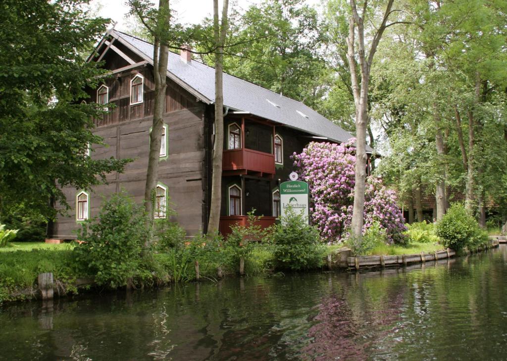 a wooden house next to a river with flowers at Logierhaus Lehde in Kaupen