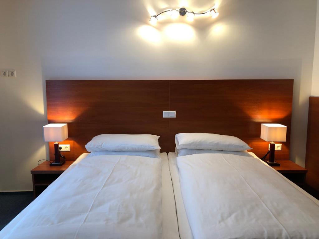 two beds in a room with two lamps on the wall at Hotel Mirabell in Erlangen