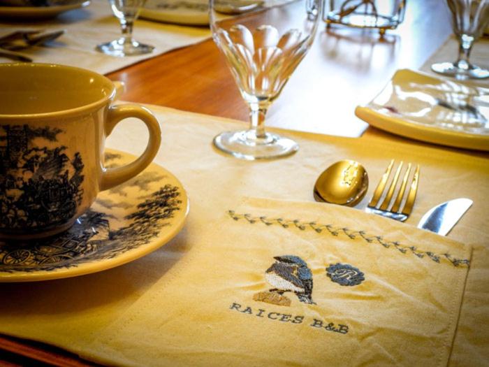 una mesa con una taza y un plato, tenedor y cuchillo en Raíces B&B Boutique en Sierra de la Ventana