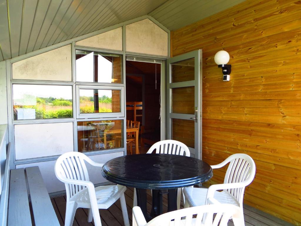 a dining room with a black table and white chairs at Tangloppen Camping & Cottages in Ishøj