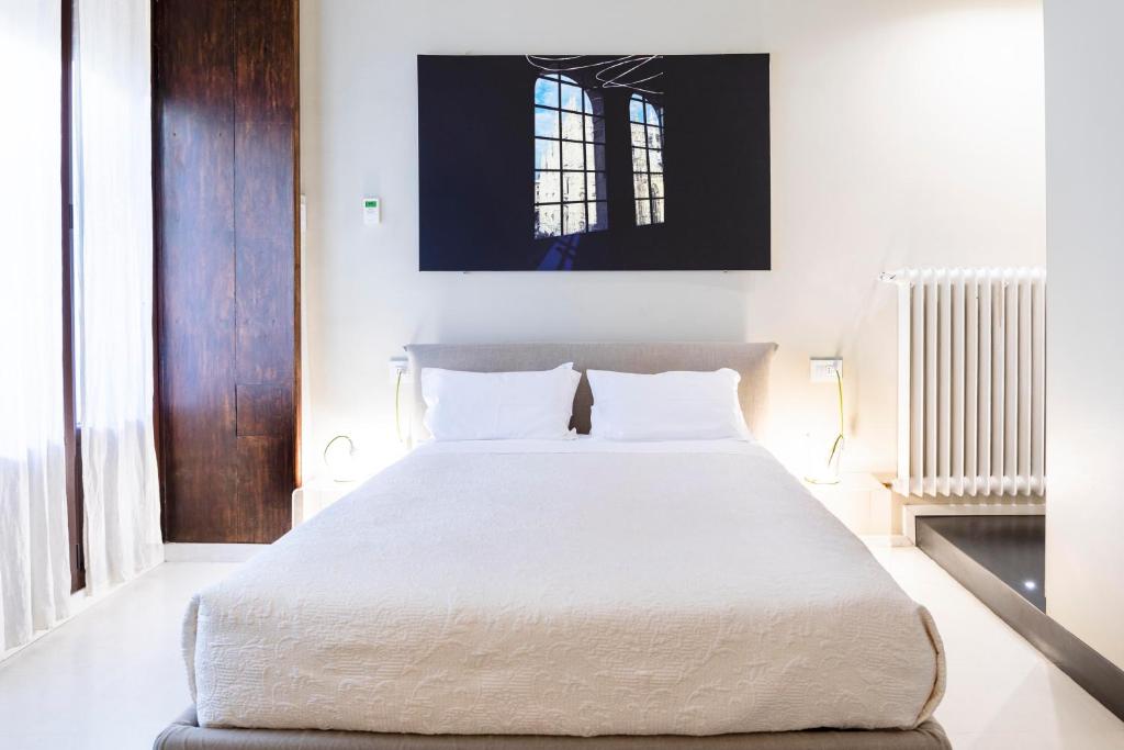 una camera da letto con un grande letto con lenzuola bianche di BC MAISON bed&cafe Milano a Milano