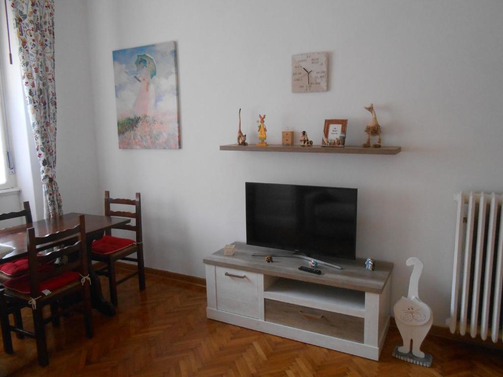 - un salon avec une télévision, une table et des chaises dans l'établissement Andrea e Valentina, à Trieste