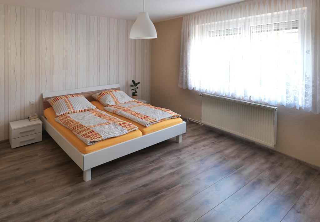 a bedroom with a bed and a window and wooden floors at Ferienhaus Wittig in Löbnitz