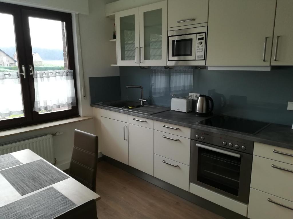 a kitchen with white cabinets and a stove top oven at Ferienwohnung Wichtelgarten in Kranenburg