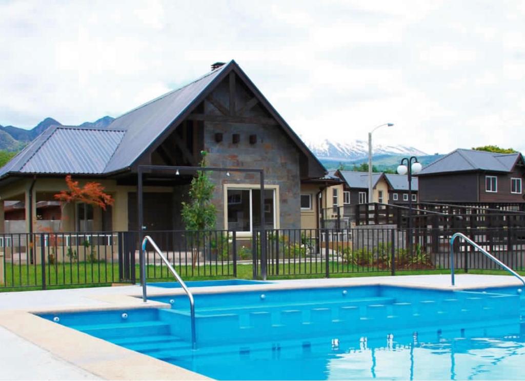 a house with a swimming pool in front of a house at Casa Condominio Los Robles II in Pucón