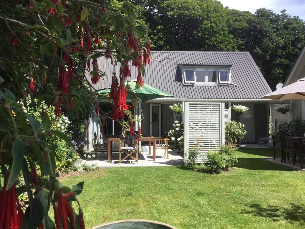 dom z ogrodem z czerwonymi kwiatami w obiekcie Sunny Glen Cottage w mieście Waikanae