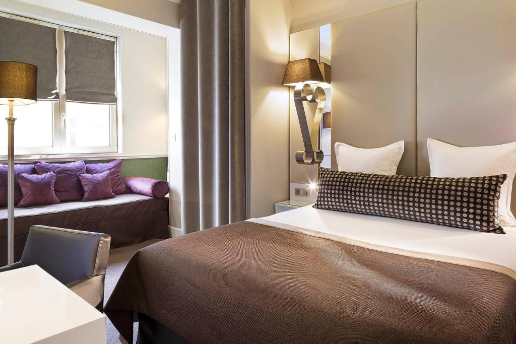 パリにあるオテル ガリレオ シャンゼリゼのベッドとソファ付きのホテルルーム