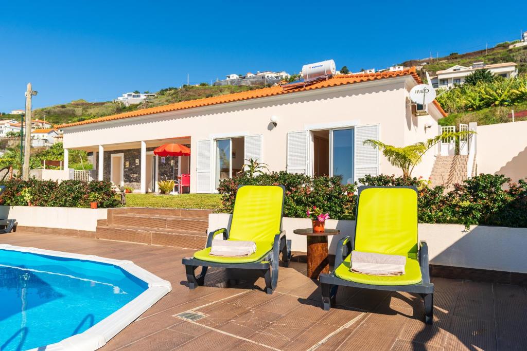 un par de sillas amarillas sentadas junto a una piscina en Casa Sol e Vista, en Arco da Calheta