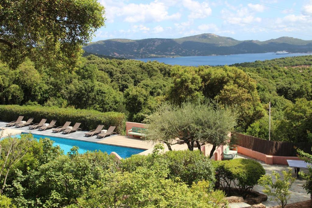 een zwembad met ligstoelen en uitzicht op een meer bij Hotel Les Hauts de Porto-Vecchio in Porto-Vecchio