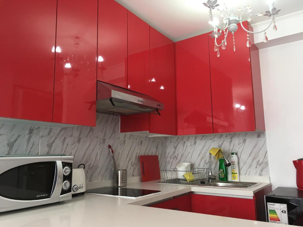 a kitchen with red cabinets and a microwave at Depto Metro Cal y Canto in Santiago