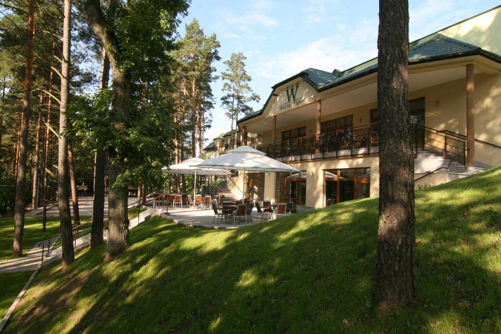 ein Haus mit Rasen und Bäumen davor in der Unterkunft Hotel nad Wigrami in Gawrych Ruda