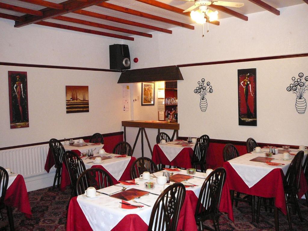 a dining room with tables and chairs with red table cloth at The Craigmore in Blackpool