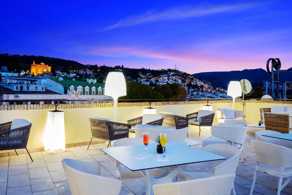 a patio with white tables and chairs on a roof at Eurostars Puerta Real in Granada