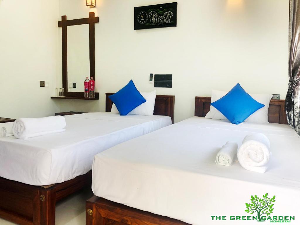 two beds in a room with blue and white pillows at The Green Garden in Dambulla