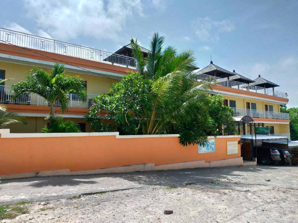 a building with palm trees in front of it at Balangan Paradise Hostel and Restaurant in Jimbaran