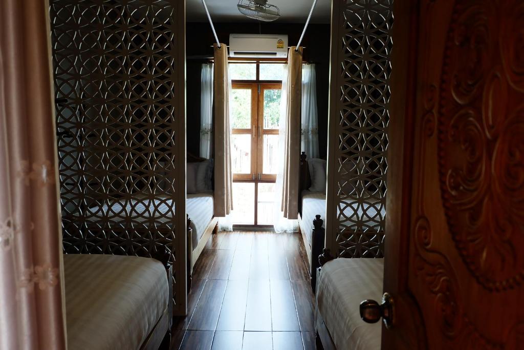 a room with two beds and a door with a window at Bloom Cafe & Hostel in Ko Lipe
