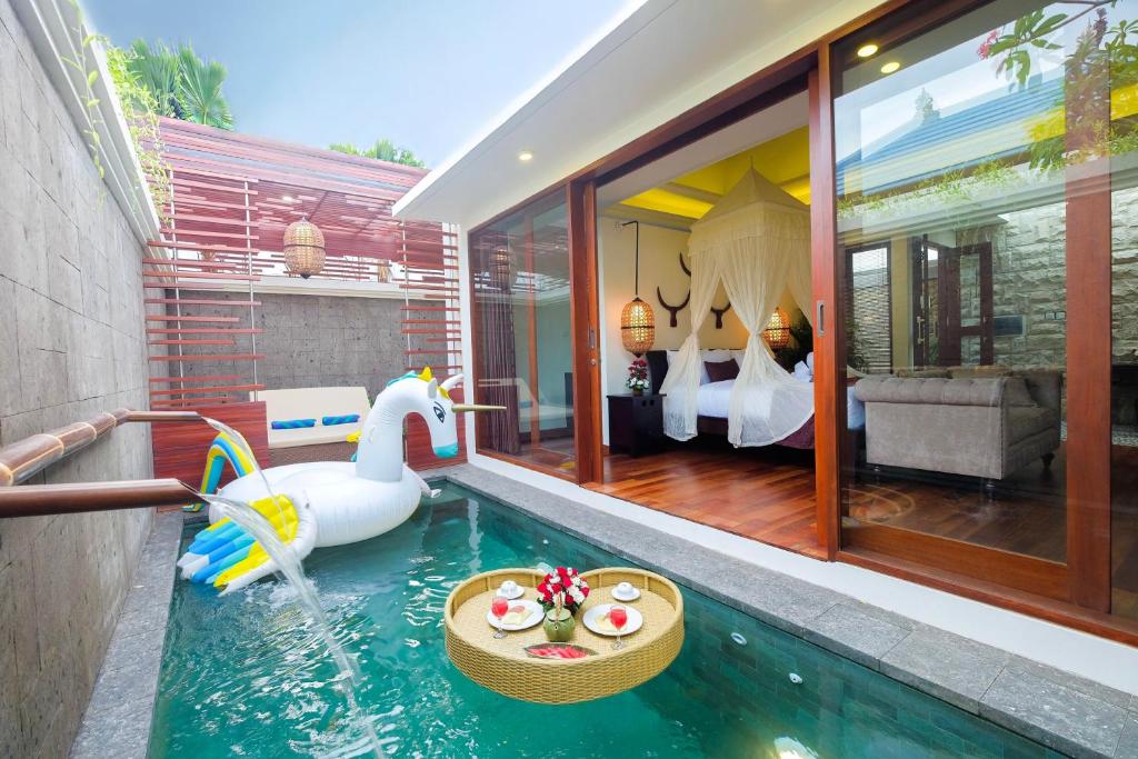 a room with a pool with a swan and a bedroom at Villa Bougainville in Seminyak