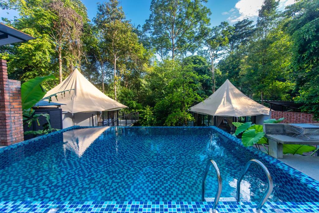 a swimming pool with two tents in a yard at Boulder Valley in Batu Ferringhi
