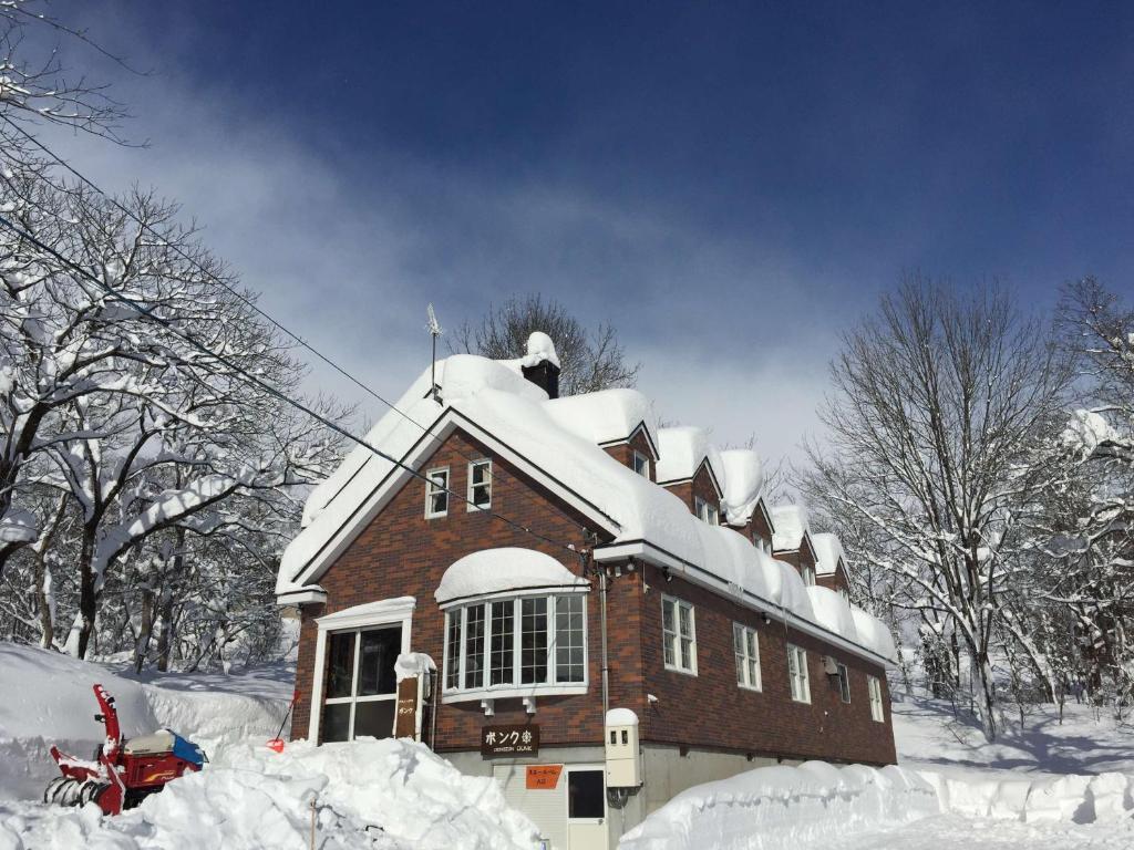 
a large white building with a snow covered roof at Guest House Bunk in Myoko

