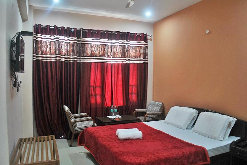 a bedroom with a bed with a red blanket and a window at Mountain and Moon, Dharamkot in Dharamshala