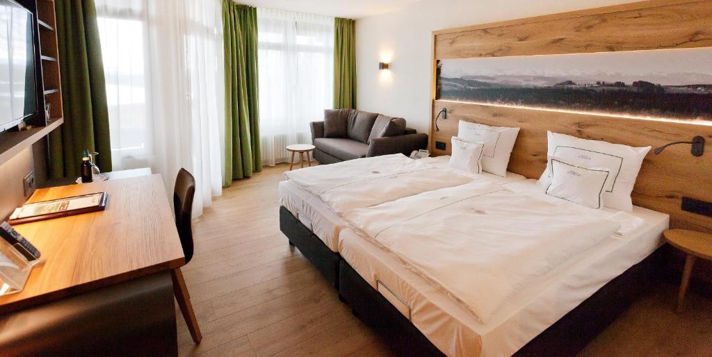 ein Hotelzimmer mit einem großen Bett und einem Stuhl in der Unterkunft Berghotel Jägerhof ****S in Isny im Allgäu