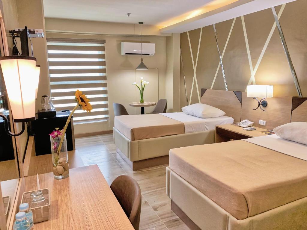 um quarto de hotel com duas camas e uma mesa em New Dawn Plus em Cagayan de Oro