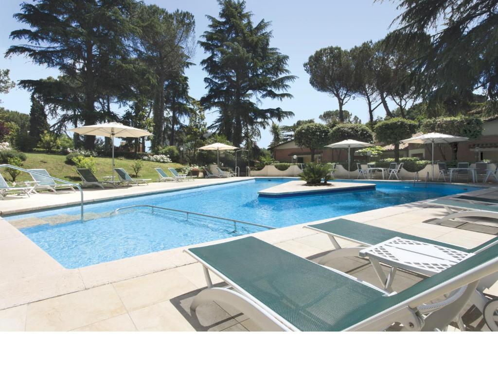 una piscina con sedie e ombrelloni di Eurogarden Hotel a Roma