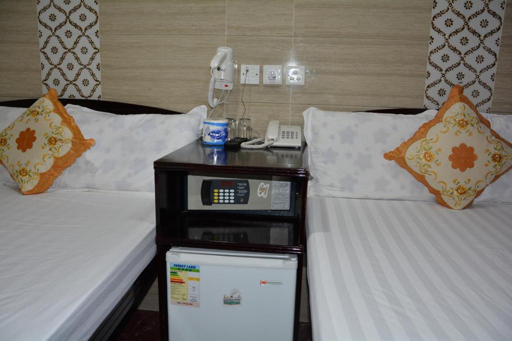a hotel room with two beds and a phone on a night stand at Everest Hostel 14/F in Hong Kong