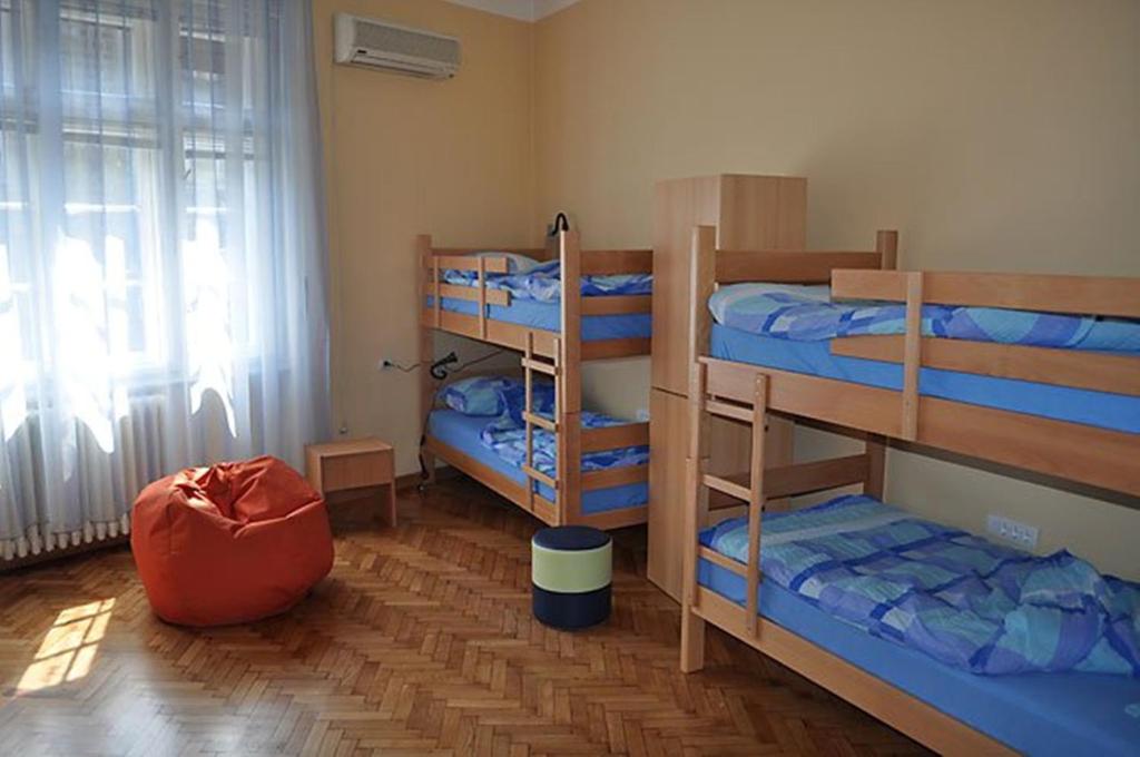um quarto com três beliches e uma janela em Habitat Hostel em Belgrado