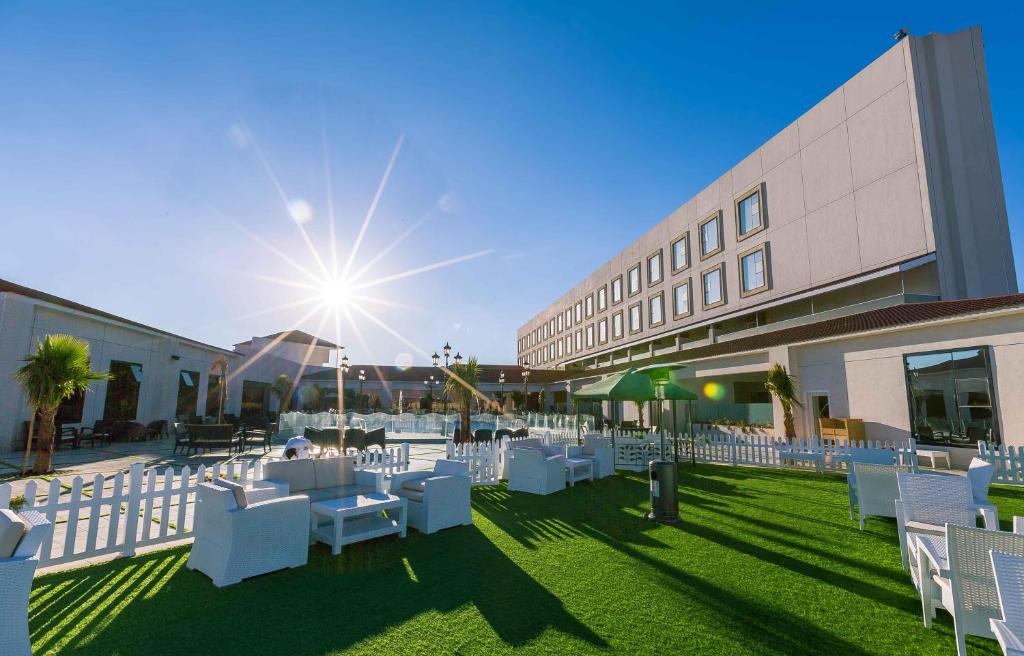 une cour avec des chaises et des tables blanches et un bâtiment dans l'établissement Iridium Hotel, à Taif