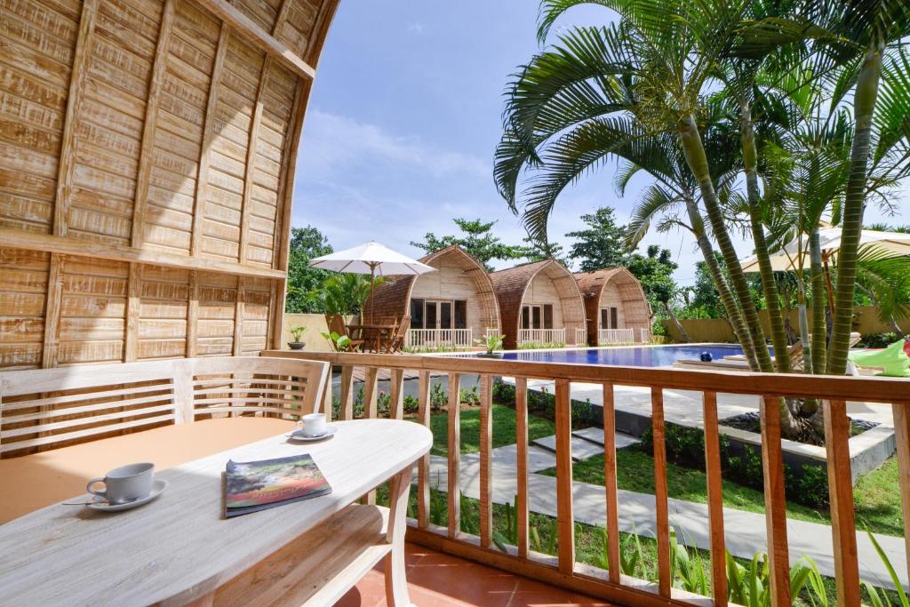 a wooden balcony with a table and a pool at Villa Del Mar Canggu in Canggu