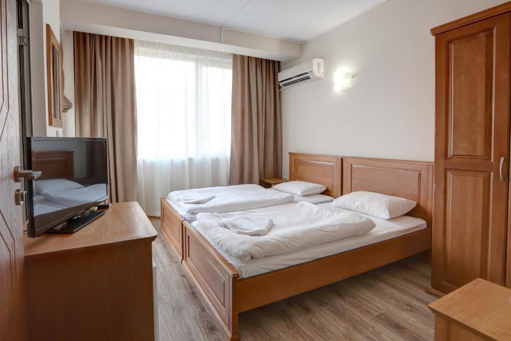 a hotel room with two beds and a television at Jupiter 1 Family Hotel in Balchik