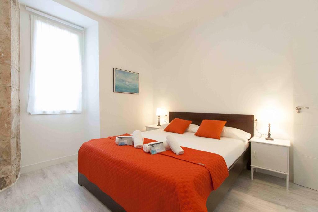 1 dormitorio con 1 cama grande con manta naranja en The Rentals Collection | Coeur, en San Sebastián