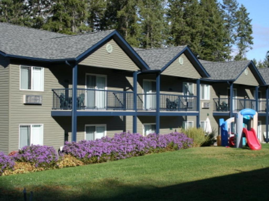 a large house with purple flowers in front of it at New Horizon Motel in Christina Lake