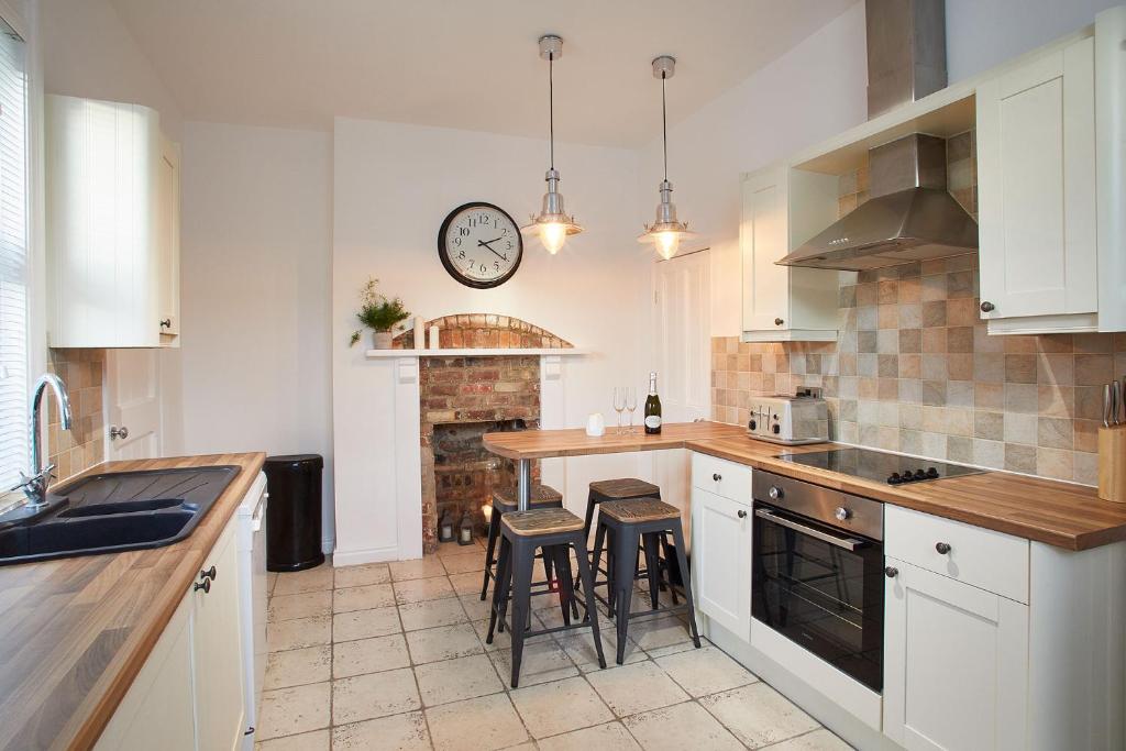 uma cozinha com armários brancos e um relógio na parede em Host & Stay - Windsor Cottage em Saltburn-by-the-Sea