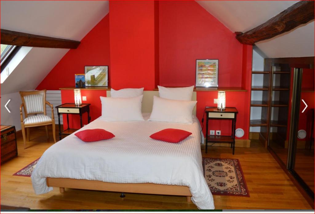 um quarto com paredes vermelhas e uma cama com almofadas vermelhas em A La Chataigneraie em Mosnes
