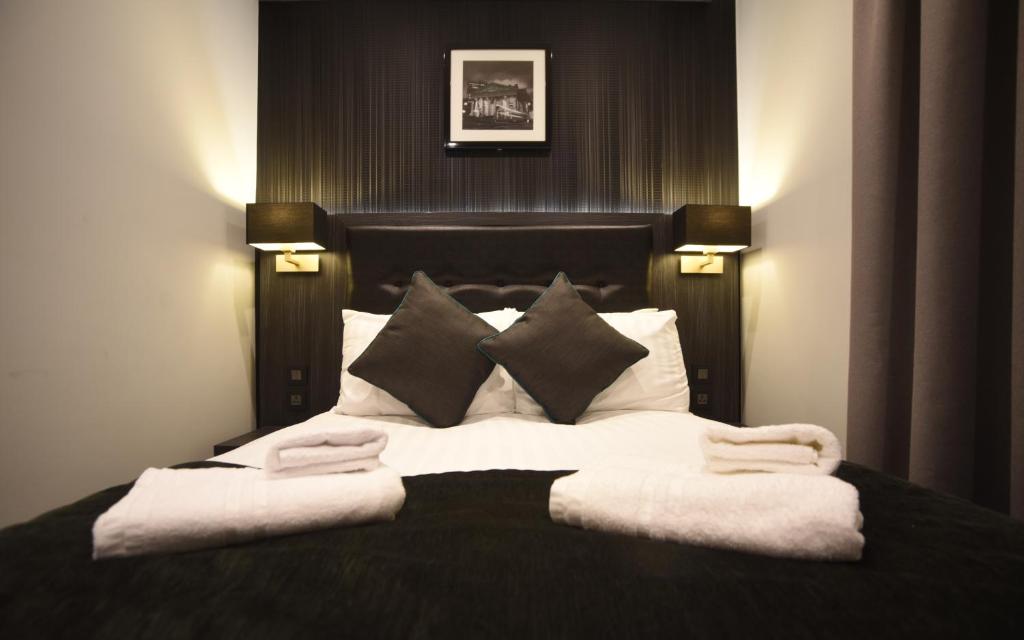 a bedroom with a large bed with white sheets and pillows at The Pack And Carriage London in London