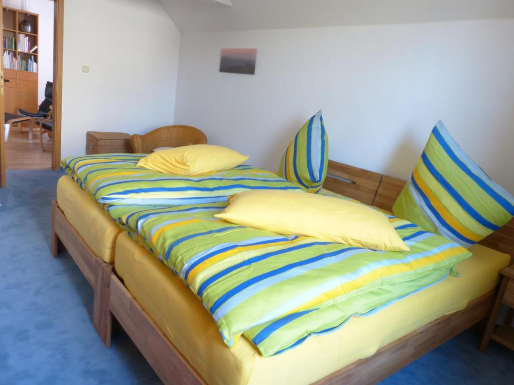 een bed met geel en blauw gestreepte lakens en kussens bij Ferienwohnung am Weyer in Solingen