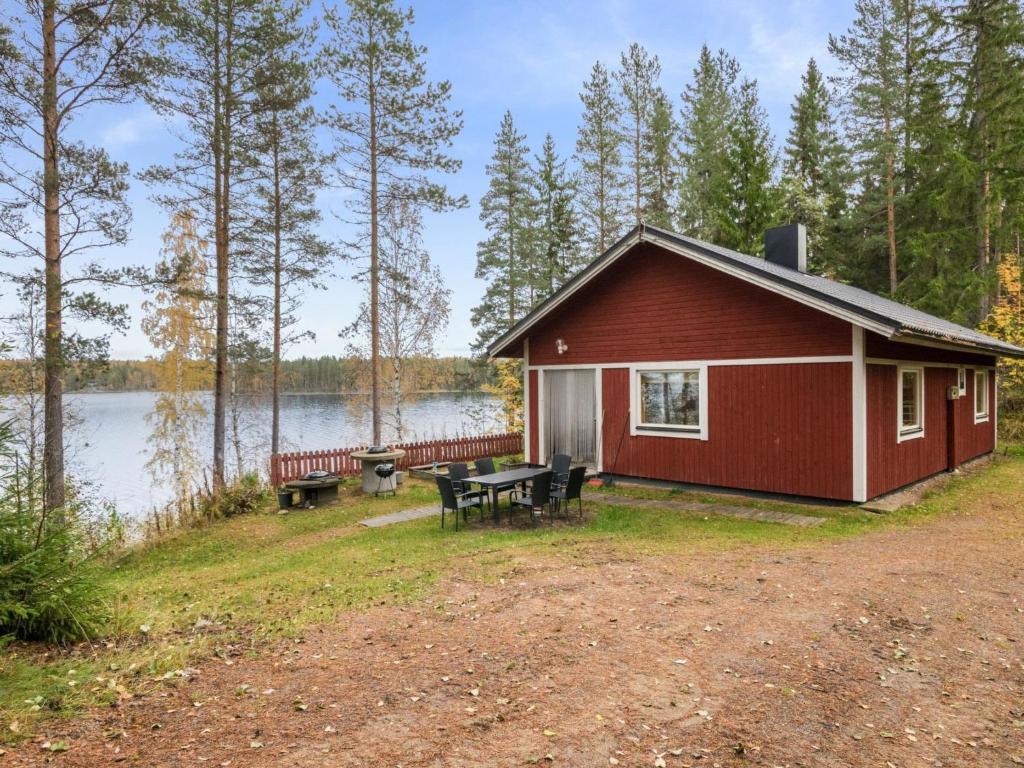 a red cabin with a picnic table next to a lake at Holiday Home Aamuntorkku by Interhome in Vuoriniemi