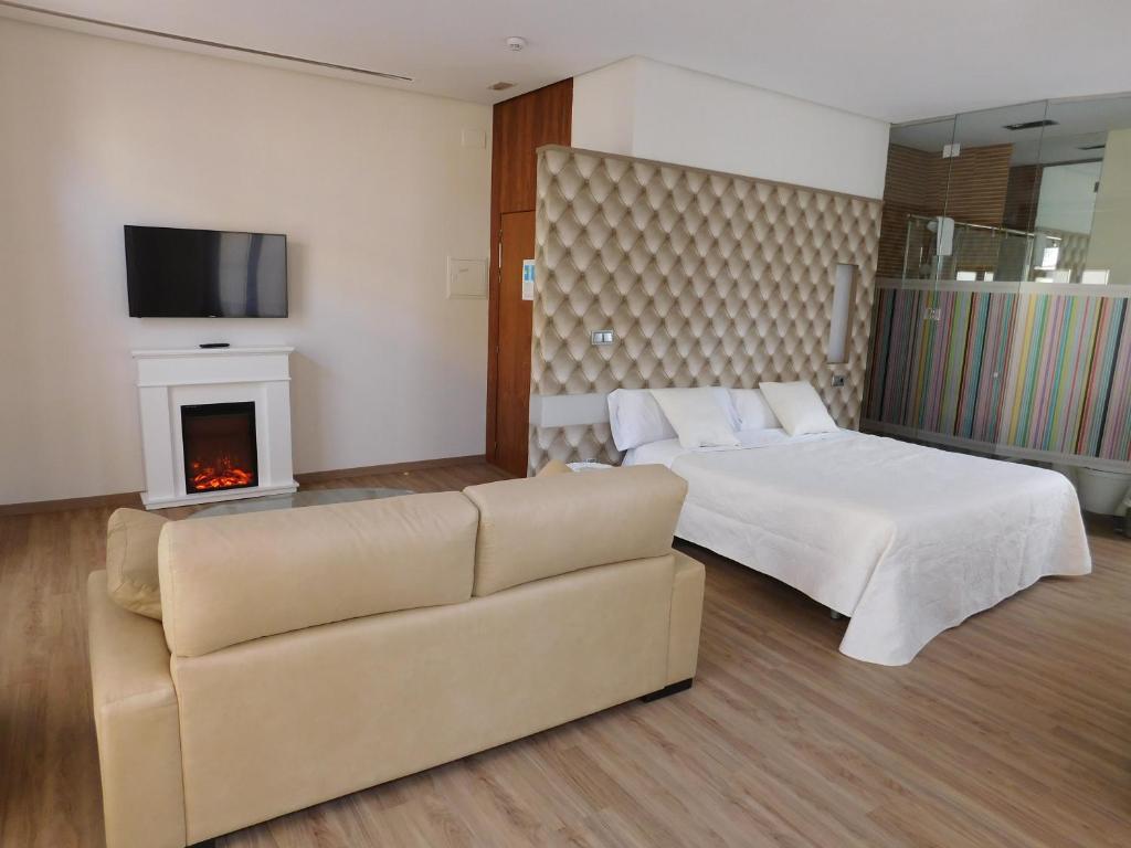 a bedroom with a bed and a couch and a fireplace at Hospedium Hotel Cañitas Maite Boutique in Casas Ibáñez