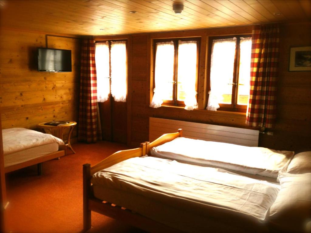 una camera da letto con un letto e due finestre di Auberge de la poste a Les Diablerets