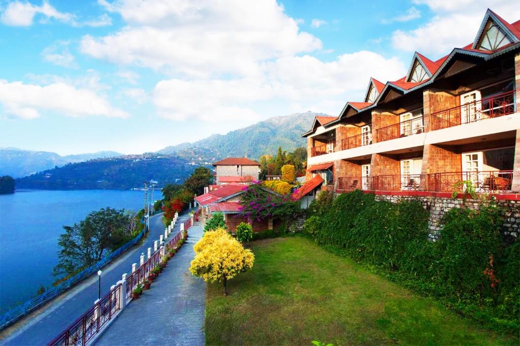 een gebouw aan de kant van een meer met bergen bij Neelesh Inn- A Luxury Lake View Hotel- 20 kms from Nainital in Bhīm Tāl