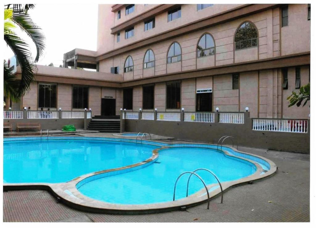 a large swimming pool in front of a building at Dhuri Resort in Vasai