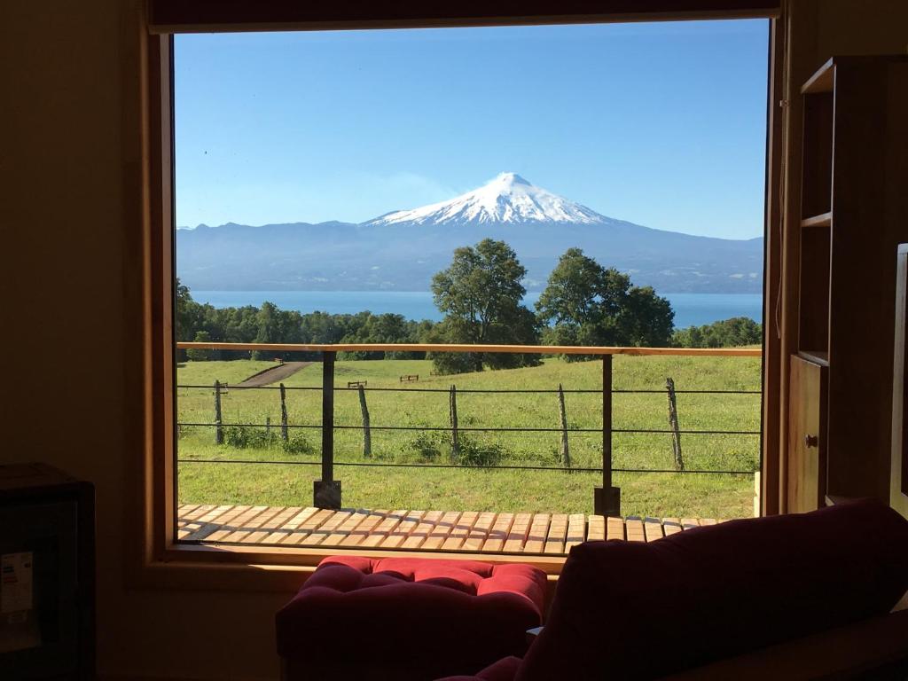a view of a snow covered mountain from a window at Karibuni - Familiar Lodging & Private Spa in Villarrica