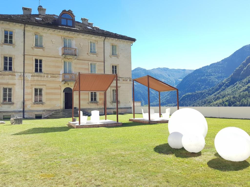 un edificio con esculturas blancas en el césped frente a él en Villa Ottocento, en Campertogno